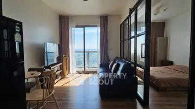 Modern open-plan living room with large windows and city view, featuring cozy seating and dining area.