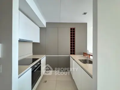 Modern kitchen with sleek cabinetry and built-in wine rack, featuring an electric stove and spacious countertops.