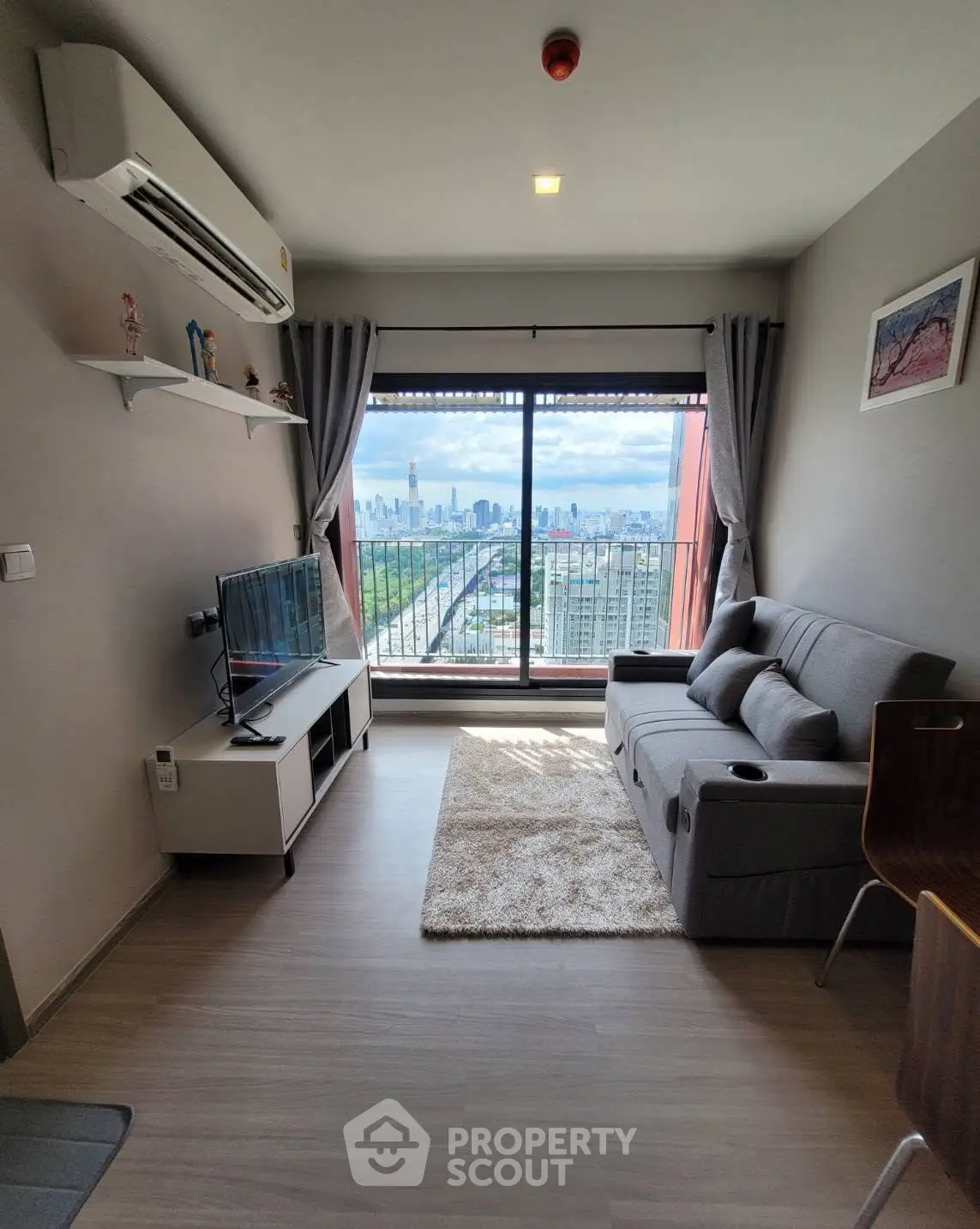 Modern living room with city view, featuring sleek furniture and large window for natural light.
