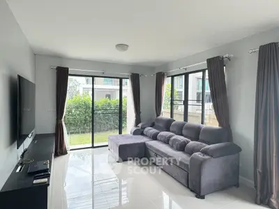 Modern living room with sleek sofa and large windows overlooking garden