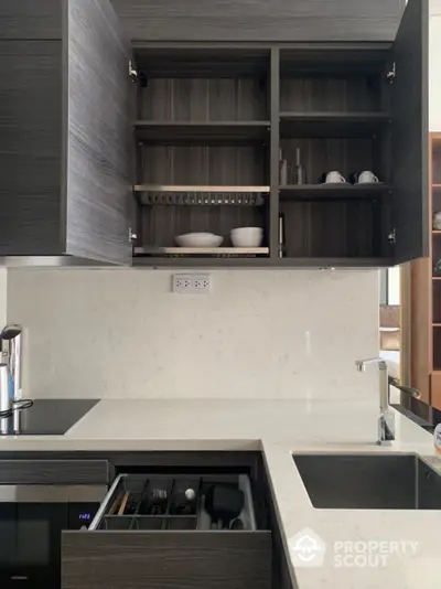 Sleek modern kitchen with dark wood cabinetry, built-in appliances, and elegant stone countertops, perfect for culinary enthusiasts.