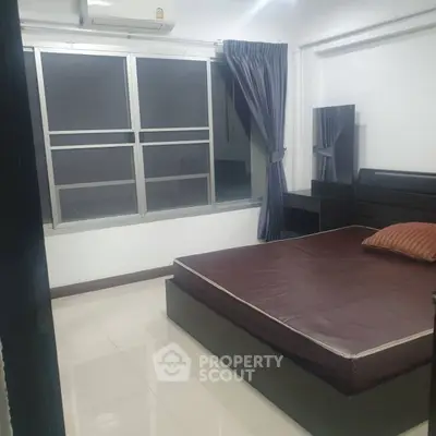 Cozy bedroom with modern furnishings and large window for natural light.