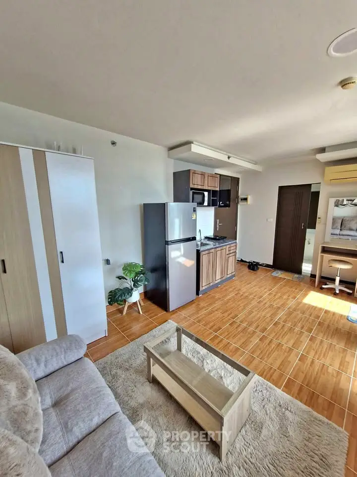 Modern open-layout living room with kitchen, featuring sleek appliances and cozy furniture.