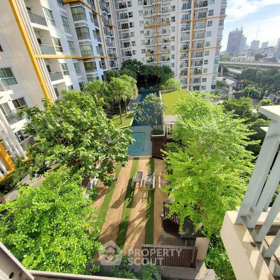 Luxurious apartment complex with lush garden and pool view in urban setting.