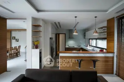 Modern open-layout kitchen with sleek design and dining area view, featuring stylish lighting and contemporary furniture.