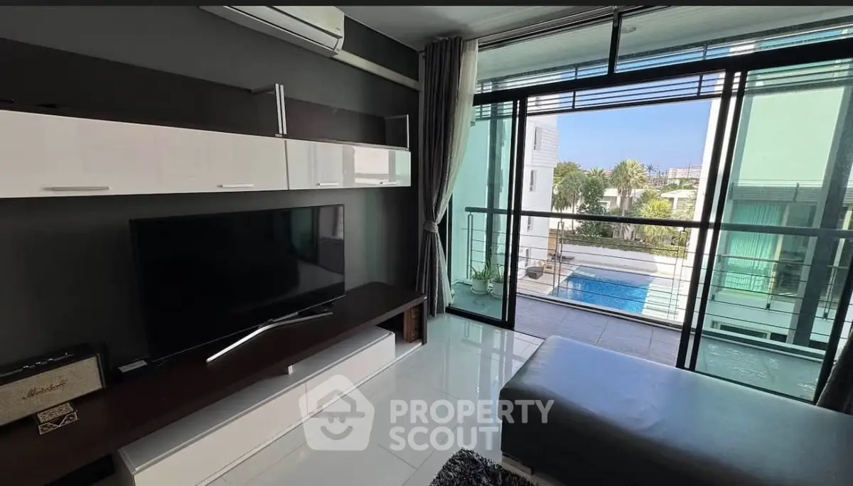 Modern living room with sleek design and pool view, featuring large windows and stylish furniture.