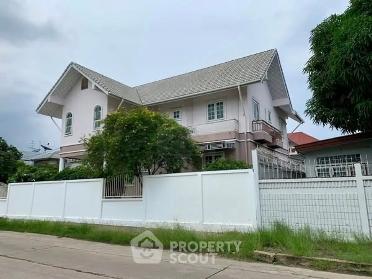 Charming suburban house with lush greenery and white fence