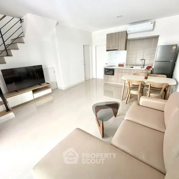 Modern open-plan living room with sleek kitchen and stylish furniture in a bright, airy space.