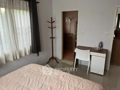 Cozy bedroom with attached bathroom and study desk, featuring natural light and modern decor.