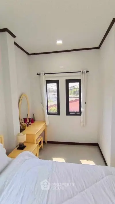 Cozy bedroom with natural light and modern decor, featuring a stylish vanity and comfortable bedding.