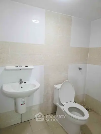 Modern bathroom with sleek white fixtures and tiled walls, ideal for contemporary living.