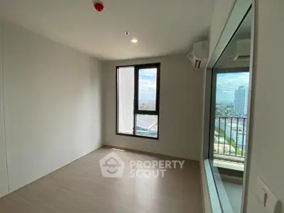 Bright empty room with large window and city view, perfect for customization.