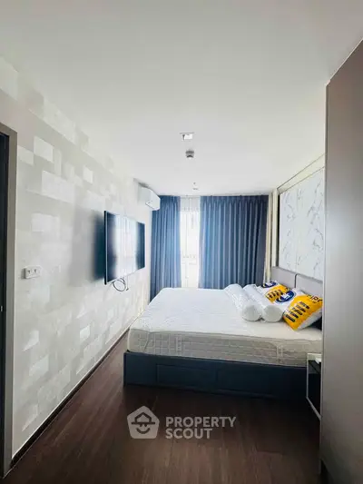 Modern bedroom with stylish decor and wall-mounted TV in a bright apartment.