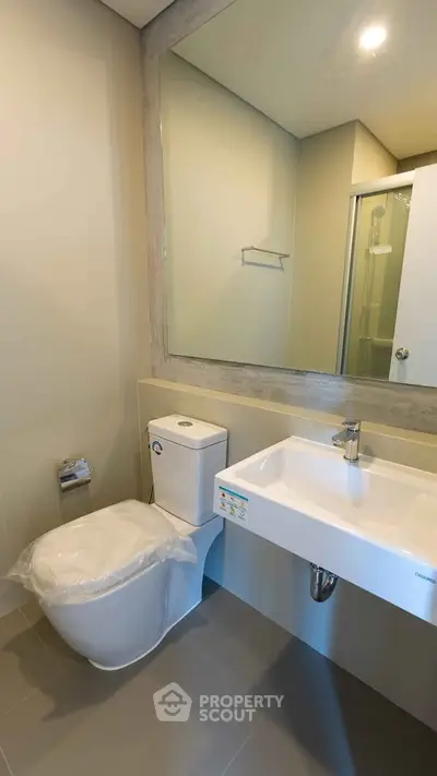 Modern bathroom with sleek fixtures and large mirror in a contemporary home.