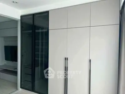 Modern minimalist bedroom with sleek built-in wardrobe and sliding glass doors.