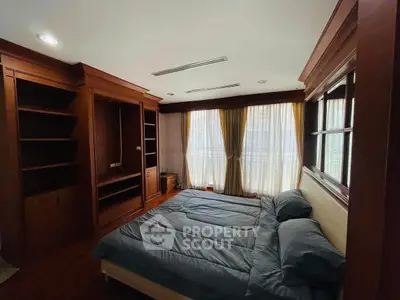 Spacious bedroom with elegant wooden furnishings and large window for natural light.