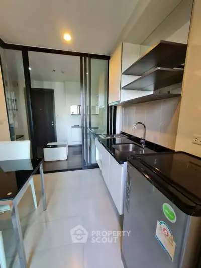 Modern kitchen with sleek cabinetry and glass partition in a stylish apartment.