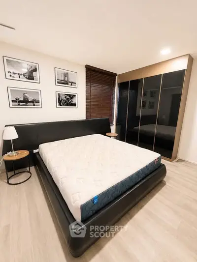 Modern bedroom with sleek black bed, stylish wardrobe, and elegant decor.