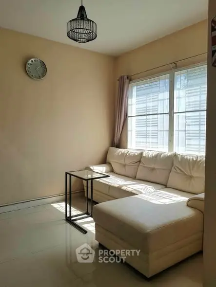 Bright living room with cozy white sectional sofa and natural light from large windows.