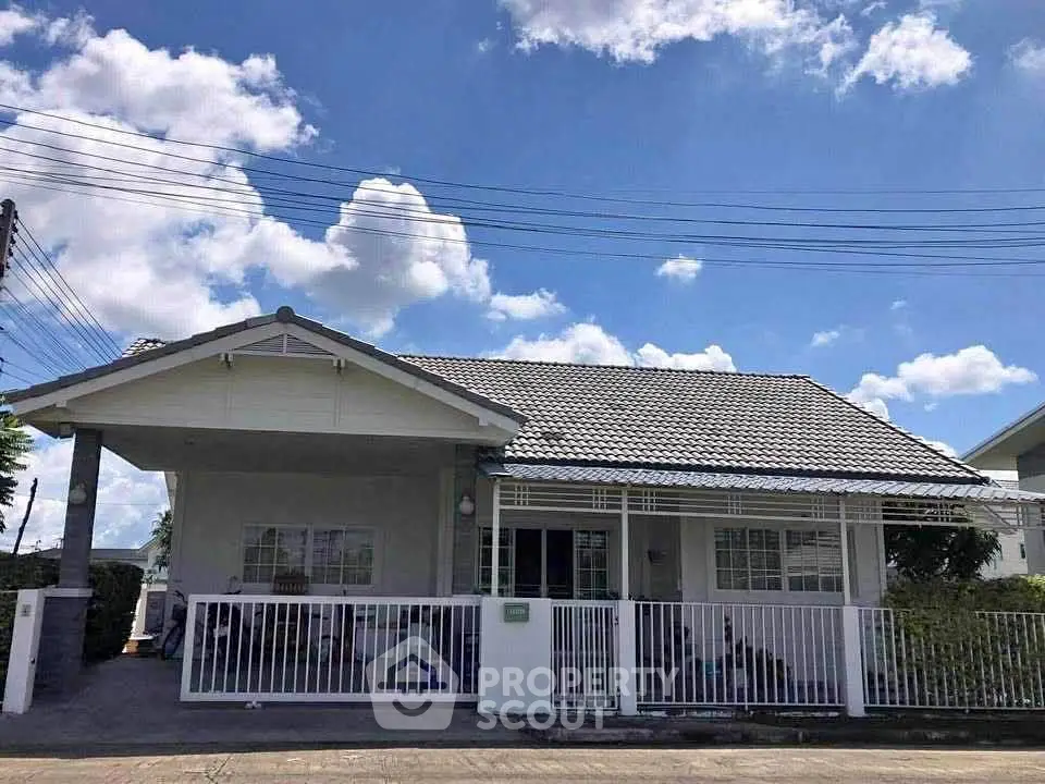 Charming single-story house with white picket fence under blue skies