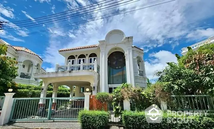 Stunning two-story villa with lush garden and spacious balcony under a clear blue sky.