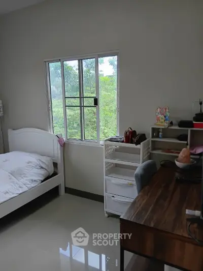 Cozy bedroom with large window and study desk, perfect for relaxation and productivity.