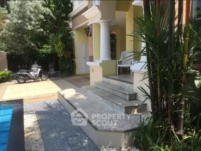 Charming villa entrance with lush greenery and inviting poolside view
