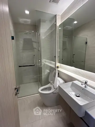 Modern bathroom with glass shower and sleek fixtures in a contemporary apartment.