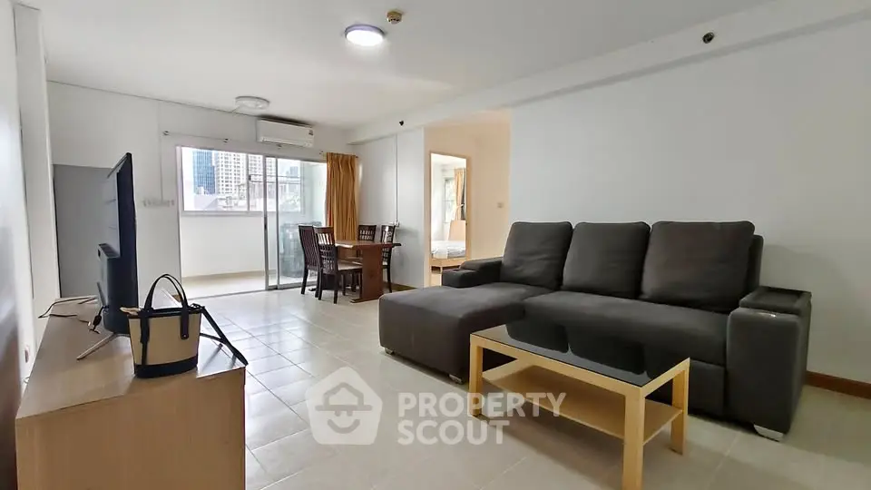 Spacious living room with modern furniture and city view balcony in urban apartment.