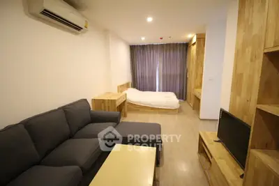 Modern studio apartment with cozy living area and stylish wooden furniture.