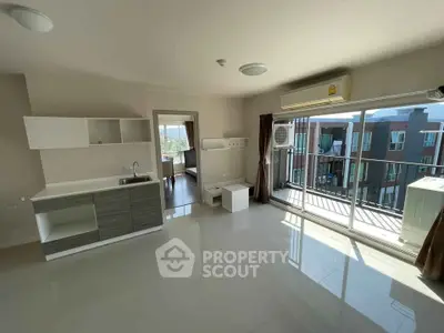 Spacious modern living room with open kitchen and balcony view in a stylish apartment.