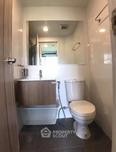 Modern bathroom with sleek fixtures and large mirror in a compact space.