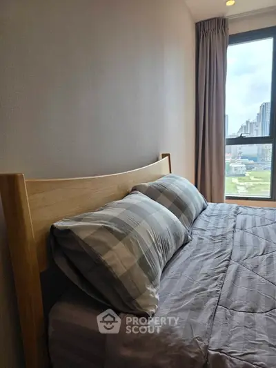 Cozy bedroom with city view, featuring a wooden bed frame and plaid bedding.