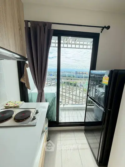 Modern kitchen with balcony view, featuring sleek appliances and scenic cityscape.