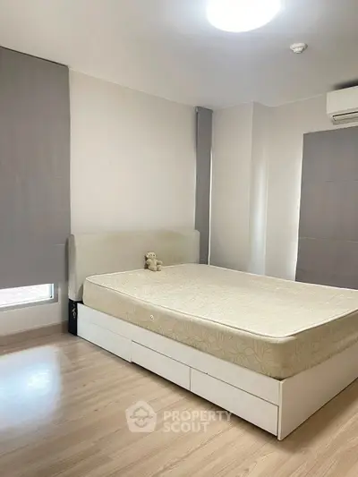Spacious bedroom with modern design and ample natural light, featuring a comfortable bed and sleek flooring.