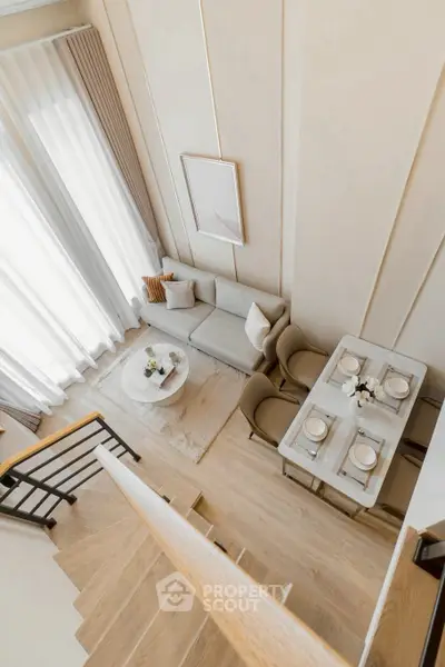 Elegant modern living room with dining area and staircase, featuring neutral tones and stylish decor.