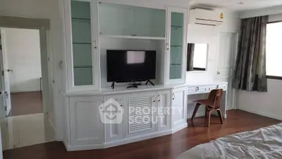 Spacious bedroom with built-in TV cabinet and wooden flooring