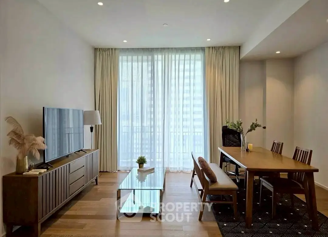 Modern living room with elegant dining area and large TV, featuring floor-to-ceiling windows.