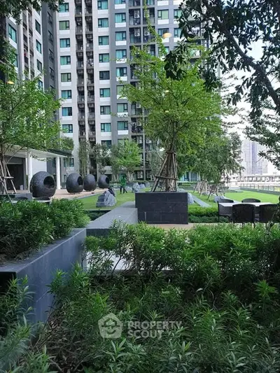 Modern apartment building with lush garden and outdoor seating area.