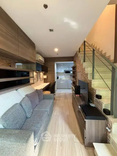 Modern living room with stylish decor and open kitchen layout, featuring cozy seating and sleek staircase.