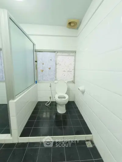 Spacious bathroom with modern white tiles and a glass shower partition.