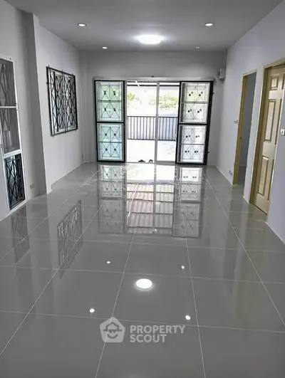 Spacious modern living room with glossy tiled floors and large windows for natural light.