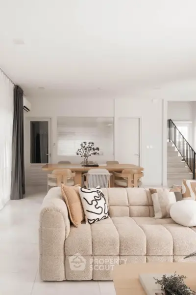 Modern living room with cozy beige sofa and elegant dining area in open layout