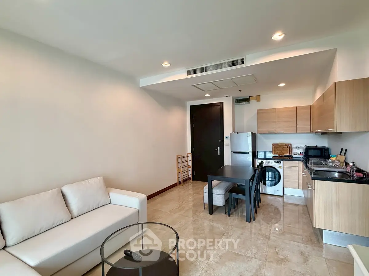 Modern open-layout living room with kitchen, featuring sleek furniture and contemporary design.