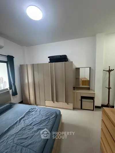 Spacious bedroom with modern furniture and ample storage in a well-lit apartment.