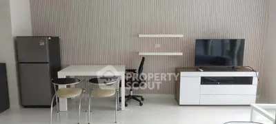 Modern living room with sleek furniture and appliances, featuring a TV and dining area.