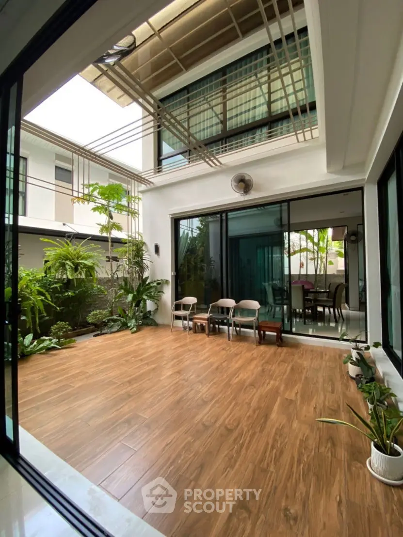 Spacious modern patio with wooden flooring and lush greenery in a contemporary home.