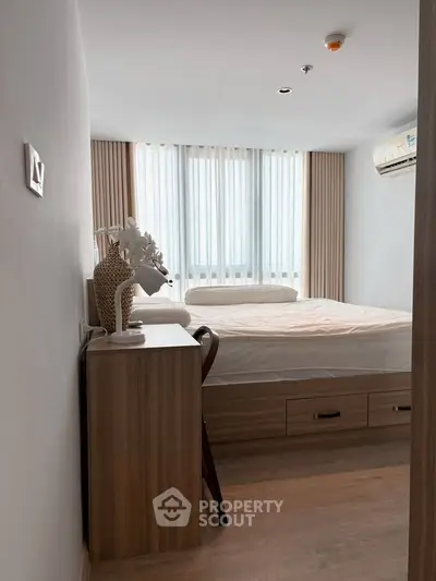 Modern bedroom with stylish decor and natural light, featuring a comfortable bed and air conditioning.