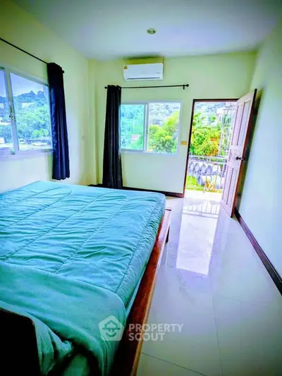 Bright bedroom with balcony and scenic view, featuring modern decor and ample natural light.