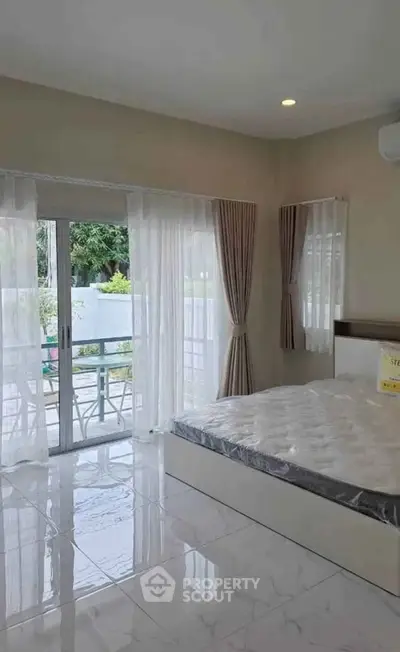Spacious bedroom with large windows and balcony access, offering natural light and serene views.